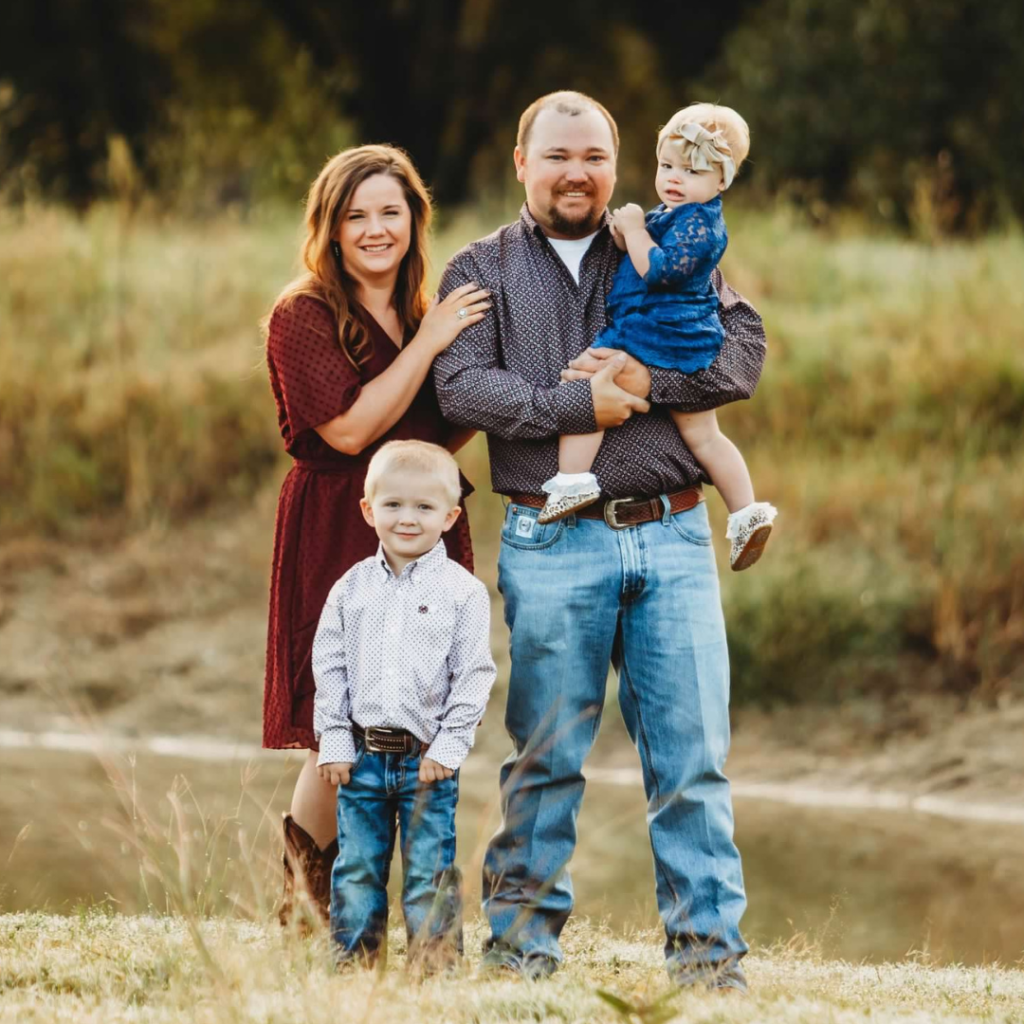 family in front of livestock tank in maroon and navy clothing