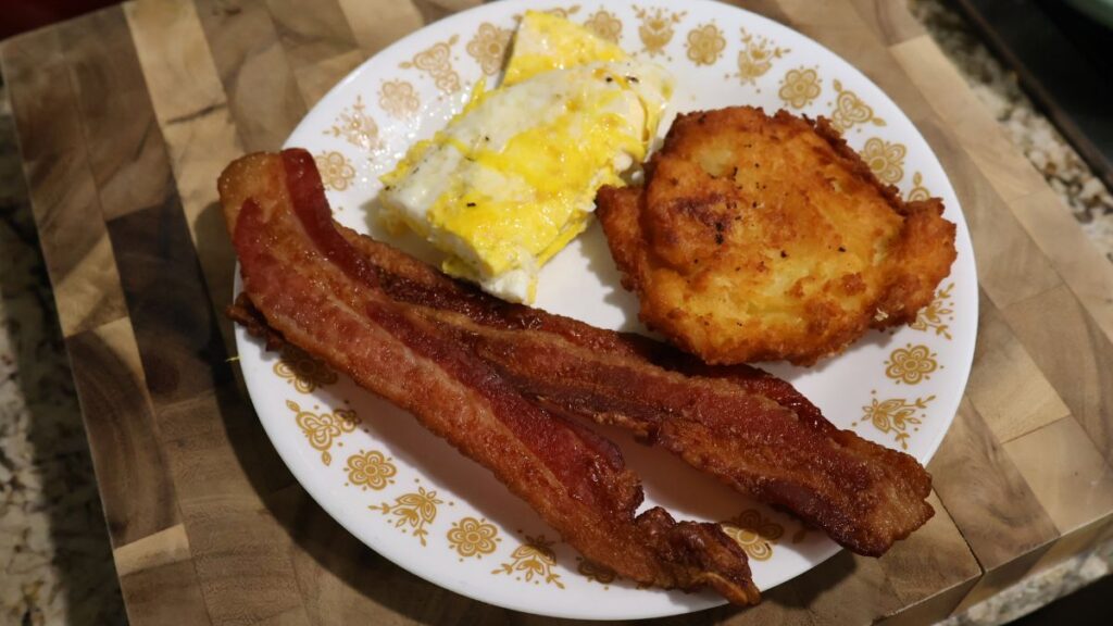 potato fritter on plate with bacon and eggs