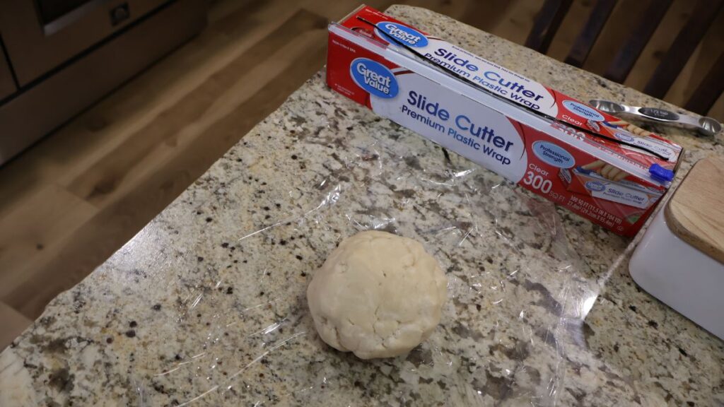 pie dough ball in plastic wrap