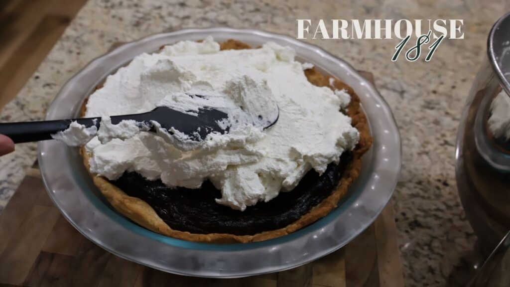 spreading homemade whipped cream on chocolate pie