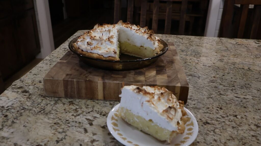 slice of coconut pie on plate and sliced pie on cutting board