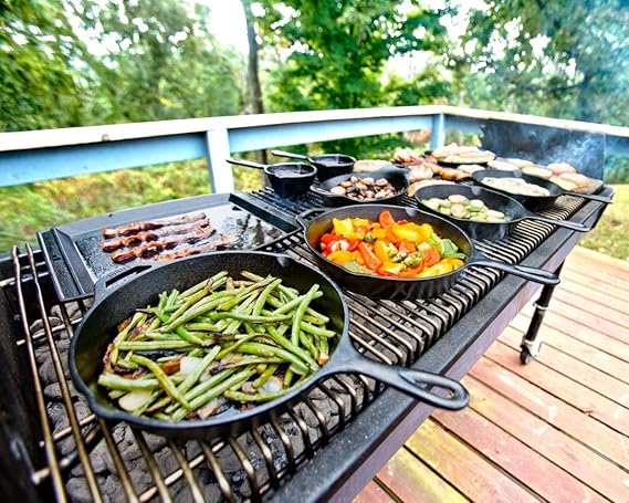 multiple Lodge cast irons on outdoor grill filled with different foods