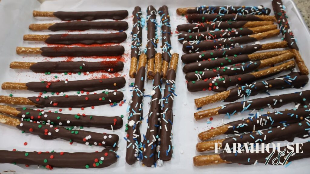 chocolate covered pretzel rods with sprinkles on sheet pan