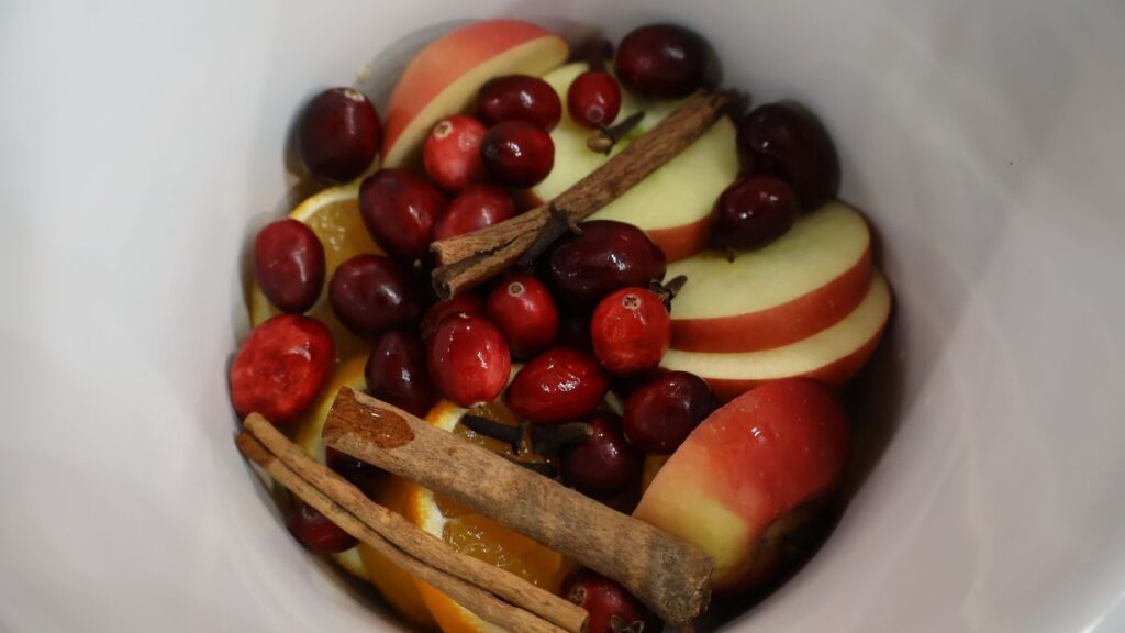 cut apples, cranberries, cut oranges, cinnamon and cloves in crock pot