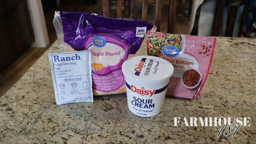 ingredients of shredded cheese, sour cream, ranch dressing mix, and bacon bits displayed