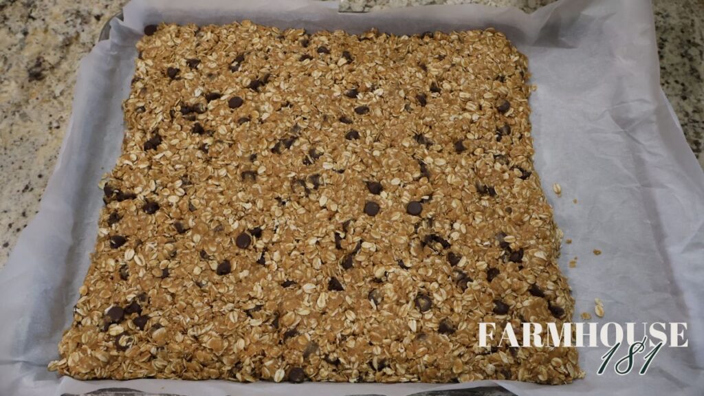 chocolate peanut butter granola bars pressed into sheet pan lined with parchment paper