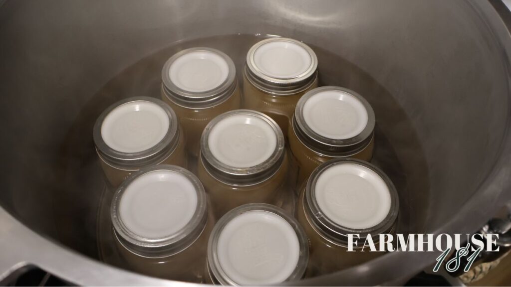 jars of chicken broth being filled and loaded into canner