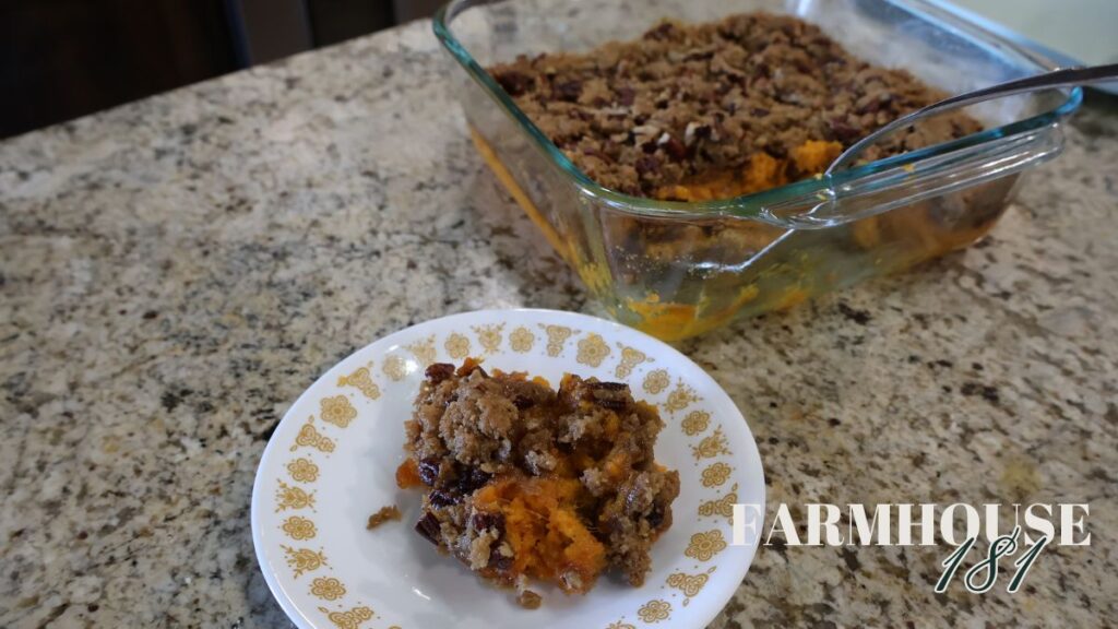 sweet potato casserole with pecan topping in pyrex dish being served from and spooned onto plate