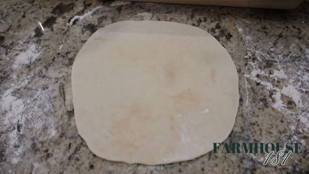 rolled out tortilla dough on floured countertop